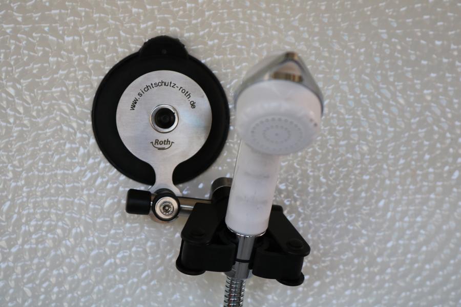 Roth flexibler Brausehalter mit Saugnapf und weißer Handbrause an einer strukturierten Oberfläche